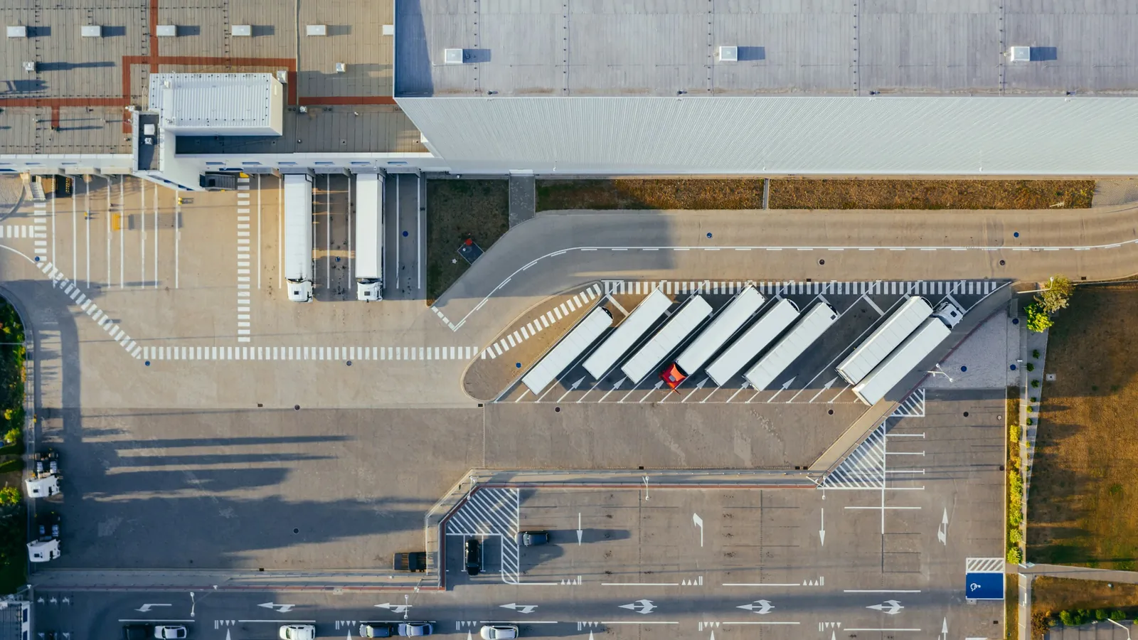 Aerial view of a distribution center with a row of trailers parked beside the loading bays.